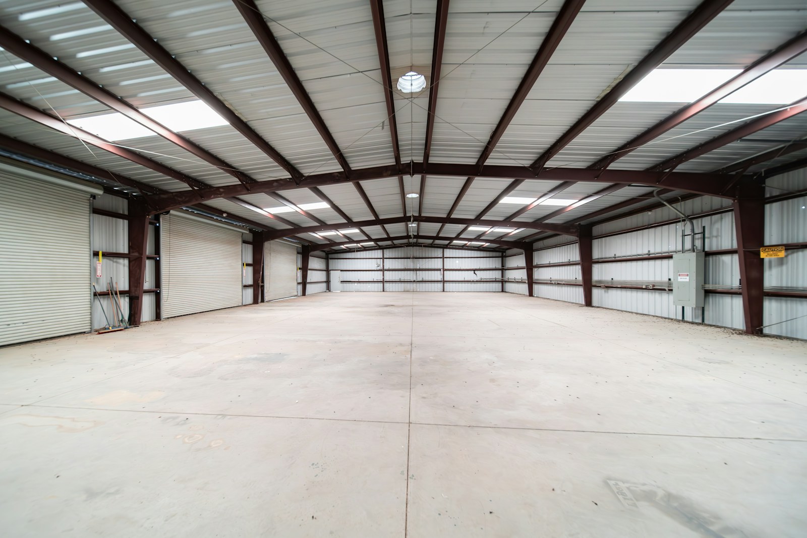 Empty modern warehouse interior with steel beams, white walls, and polished concrete floor